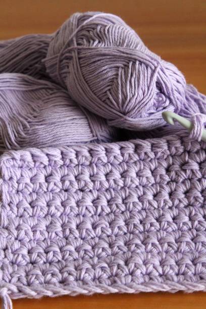 istock Crochet work: trivet or potholder made of lavender cotton yarn. Crochet hook. Solid stitches. A pretty souvenir or gift. 1403308421