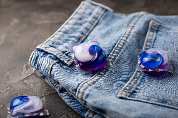 istock Laundry capsules with blue jeans on a black marble background. Laundry detergent for washing clothes in a washing machine. The concept of purity. Place for text. 1403311128