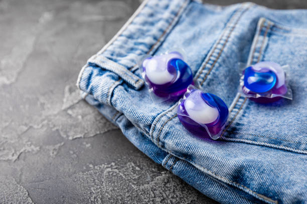 istock Laundry capsules with blue jeans on a black marble background. Laundry detergent for washing clothes in a washing machine. The concept of purity. Place for text. 1403311270