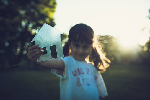 Little girl in a park holding a transparent house shape