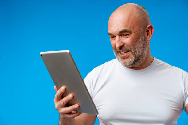 istock Handsome middle age man with digital tablet against blue background 1403316120