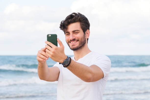 istock Happy man taking selfie using mobile phone at beach on outdoor 1403319251
