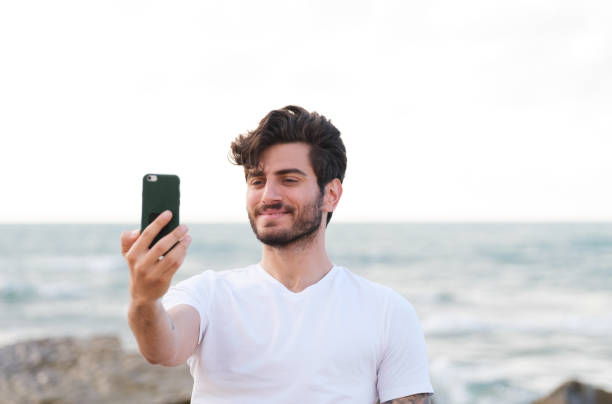 istock Happy man taking selfie using mobile phone at beach on outdoor 1403319798