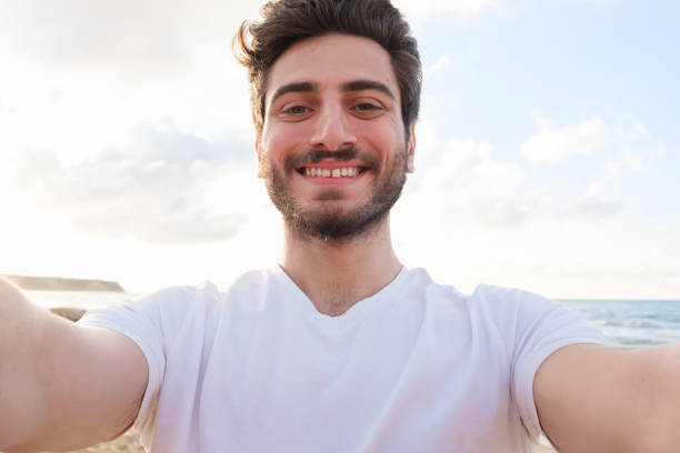 istock Happy man taking selfie using mobile phone at beach on outdoor 1403319861