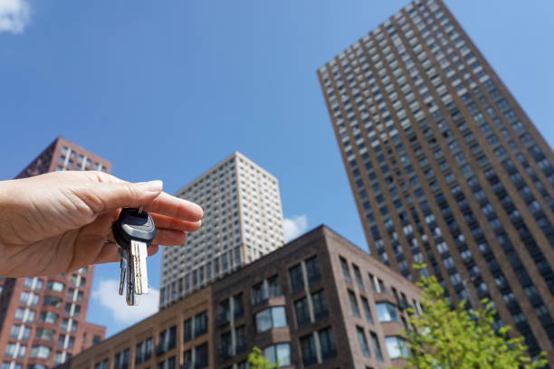 apartment keys witn a new modern residential buildings in the background - real estate imagens e fotografias de stock