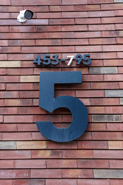 istock Entrance and apartment numbers and security camera on the brick wall outside 1403321861