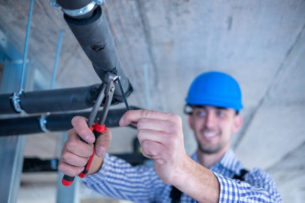 istock Young cheerful construction worker works with pliers over air conditioning unit at construction site. 1403324424