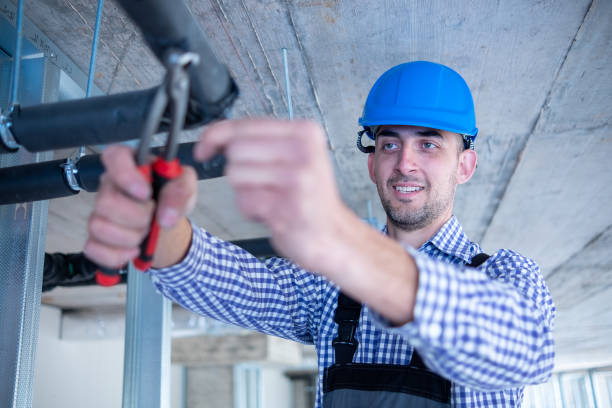 istock Young cheerful construction worker works with pliers over air conditioning unit at construction site. 1403324426