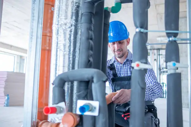 Photo of A cheerful plumber works at a construction site.