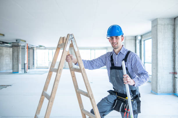 istock Young cheerful construction worker next to construction ladder at construction site. 1403324986