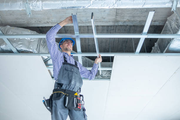 istock Young cheerful construction worker with large spirit level in his hands on to construction ladder at construction site. 1403324990