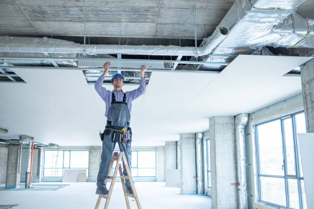 istock Young cheerful construction worker with large spirit level in his hands on to construction ladder at construction site. 1403324999