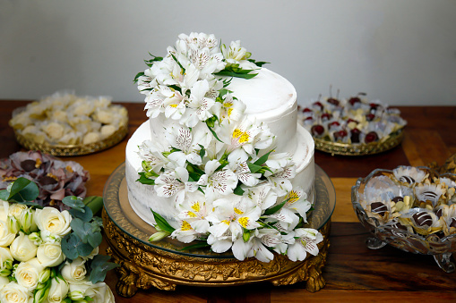 White wedding cake decorated with roses,lace and a bird couple