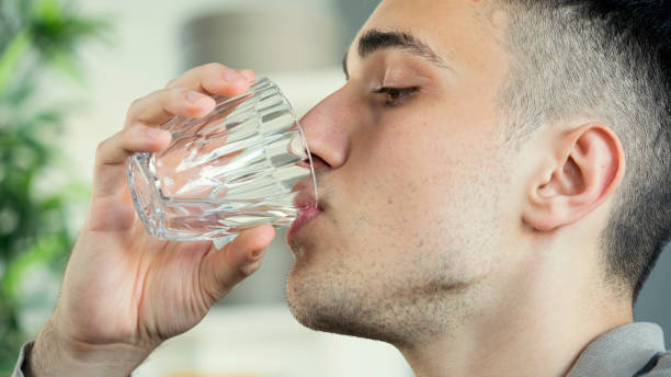 istock Young man drinks a glass of water 1403325259