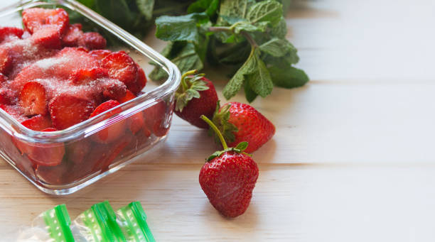 istock Red ripe freshly picked strawberries and packages for freezing on a white table. 1403325403