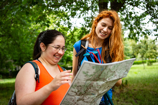 Two young woman hiking together in nature looking at map