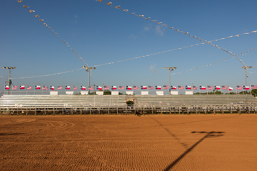 A rodeo arena in Texas is decorated with United States and Texas flags. Rodeo is part of the Texas western culture.