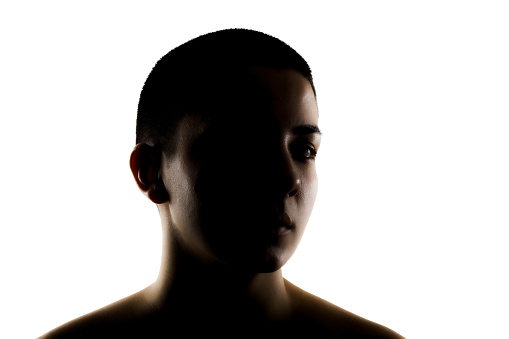 Silhouette portrait of a beautiful young woman with very short hair against white background.