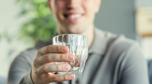 istock Young man drinks a glass of water 1403332581