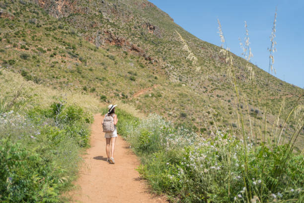 istock Young woman wearing hat and backpack walks above sea, 1403335911