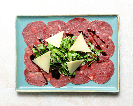 Marbled beef carpaccio with arugula and parmesan cheese.
