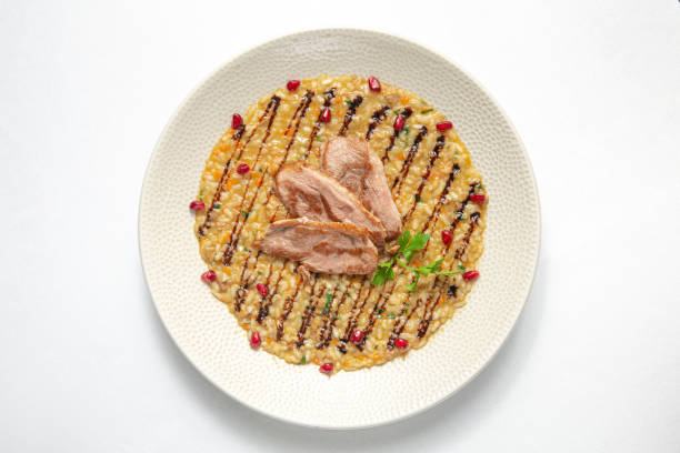 Risotto with duck slices on white background. Top view.