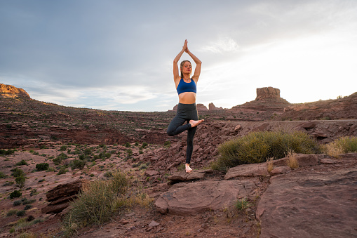 .Beautiful Young Woman Striking A Tree Pose While Practicing Yoga In The Desert Near Moab, Utah