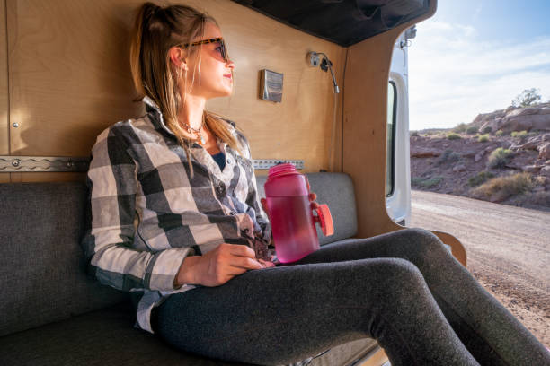 istock Beautiful Young Woman Relaxing In Her Conversion Van Drinking Water From a Water Bottle After A Great Hike Near Moab, Utah 1403341194