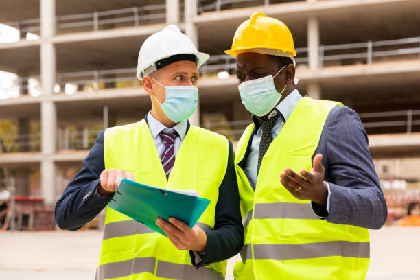 istock Portrait of an engineer and architect in protective mask with folder of documents at construction site 1403341376