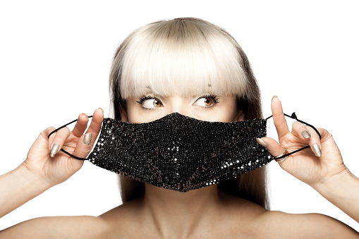 Beautiful brunette girl with blond hair fringe bangs wearing black fashionable protective face mask.