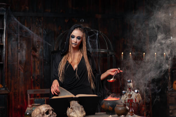 halloween, sorcière utiliser un livre magique et un chaudron préparer un poison ou une potion d’amour - sorciere potion photos et images de collection
