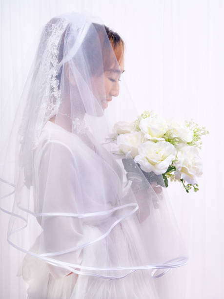 istock bride in white gown with veil holding flower bouquet 1403356302