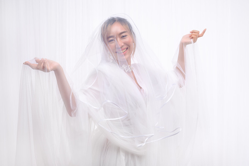 studio portrait of asian bride in white gown with veil posing on white background
