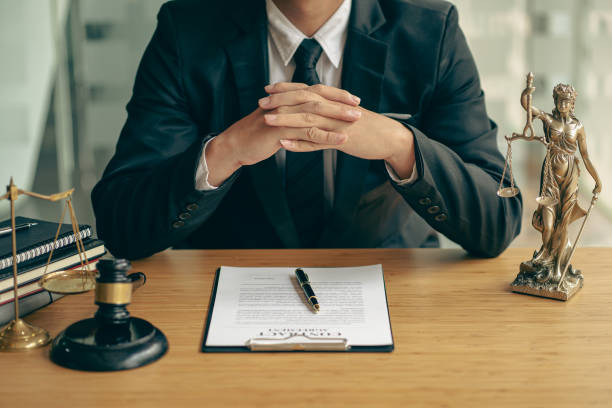 Concepts of justice and lawyers discuss contract paperwork with brass scales on a table with a judge's hammer placed in front of lawyers in the office. Legal, advice, justice, and conceptual services. stock photo
