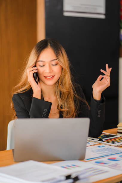 istock Asian businesswomen using computers at work Women start working with business plan report papers at the office. Young entrepreneur talking on smartphone. Official consultant vertical picture 1403374503