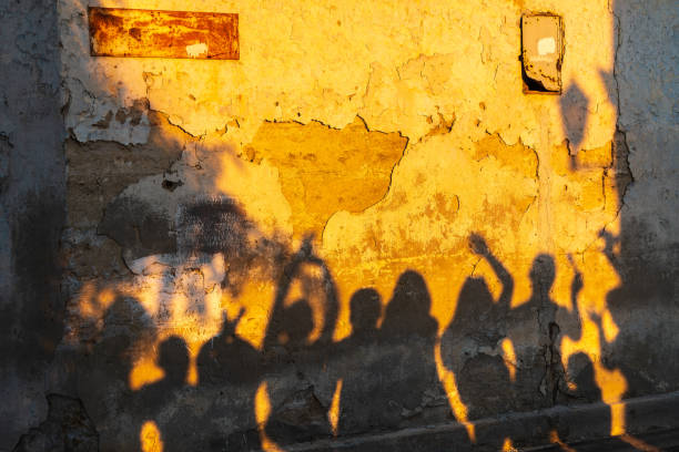 istock Shadows of dancing people on an old stone wall at sunset time. 1403381500