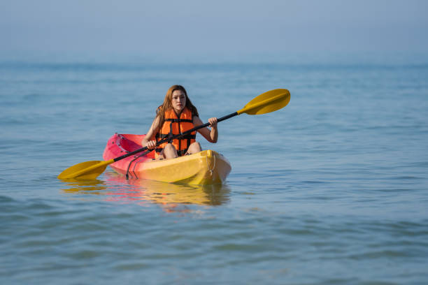 женщина в спасательном жилете гребет на байдарке в море - women kayaking life jacket kayak стоковые фото и изображения