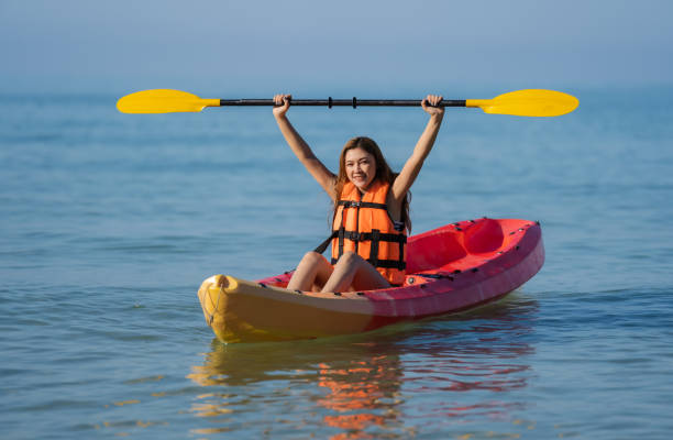 женщина в спасательном жилете гребет на байдарке в море - women kayaking life jacket kayak стоковые фото и изображения