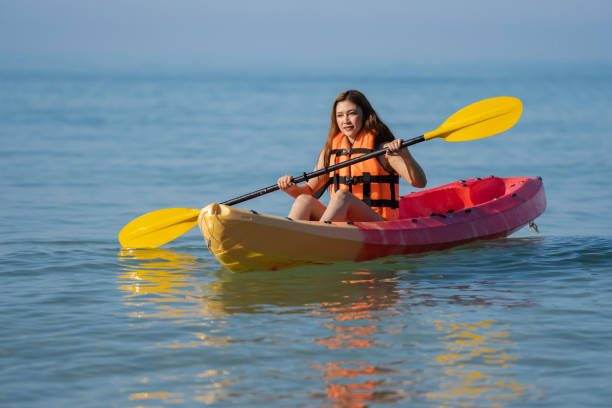 женщина в спасательном жилете гребет на байдарке в море - women kayaking life jacket kayak стоковые фото и изображения