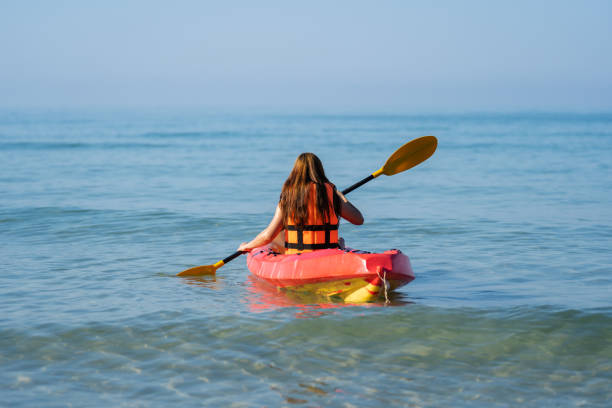 женщина в спасательном жилете гребет на байдарке в море - women kayaking life jacket kayak стоковые фото и изображения