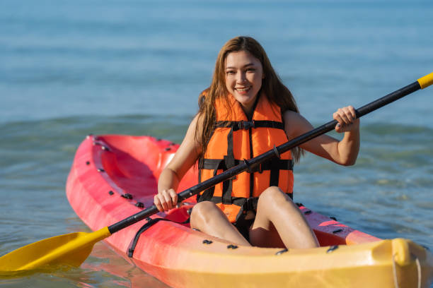 женщина в спасательном жилете гребет на байдарке в море - women kayaking life jacket kayak стоковые фото и изображения