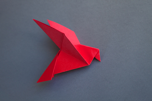 Red paper crane surrounded by the bunch of blue paper cranes. Horizontal framing, AdobeRGB photo.