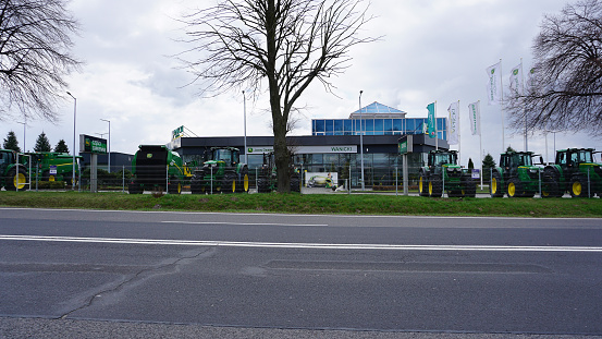 Wroclaw, Poland - April 18, 2022: The Powerful tractors at John Deer store. Row of brand new John Deere tractors outside the store of local consortium, exhibition of latest agricultural machinery.