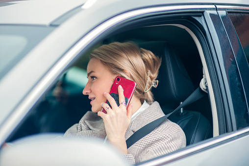 Beautiful blonde business woman driving a car speaks on the phone
