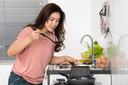 happy young woman cooking and preparing food in the kitchen at home