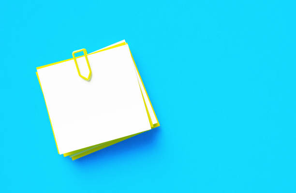 Yellow and white adhesive notes sitting on blue background. Horizontal composition with copy space.