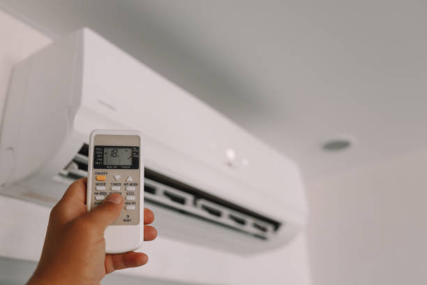 Hand is holding a remote control of air conditioner