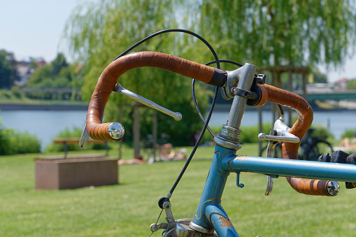 Front end of an old racing bike with handlebar tape made of brown leather on the Neckar meadow in Heidelberg.