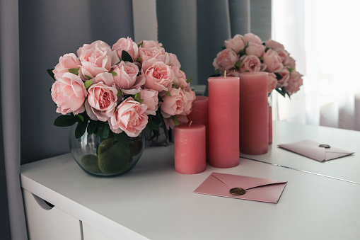 Pink letter on a female desktop, a bouquet of roses and candles.