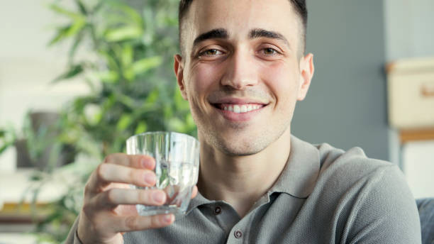 istock Young man drinks a glass of water 1403402430